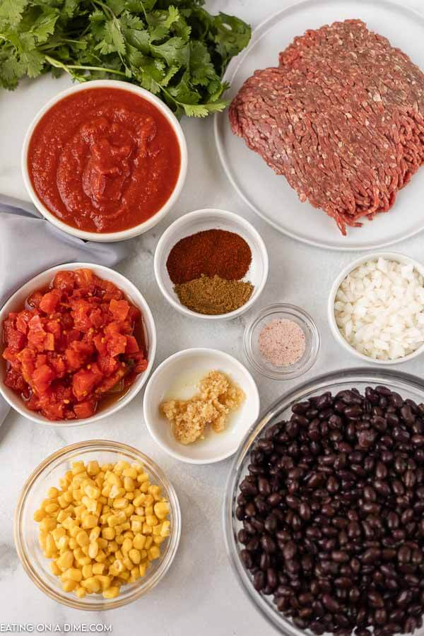 Ingredients for soup: tomatoes, ground beef, seasoning, corn, black beans, onion, garlic. 