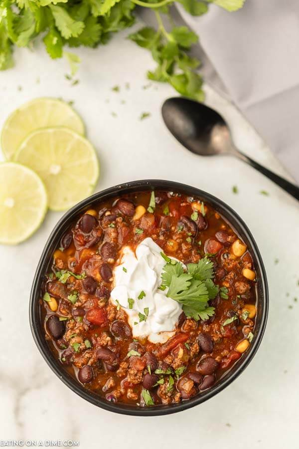 Black bean soup with cilantro topped with sour cream in a bowl. 