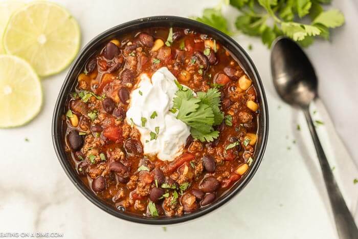 Black bean soup with cilantro topped with sour cream in a bowl. 