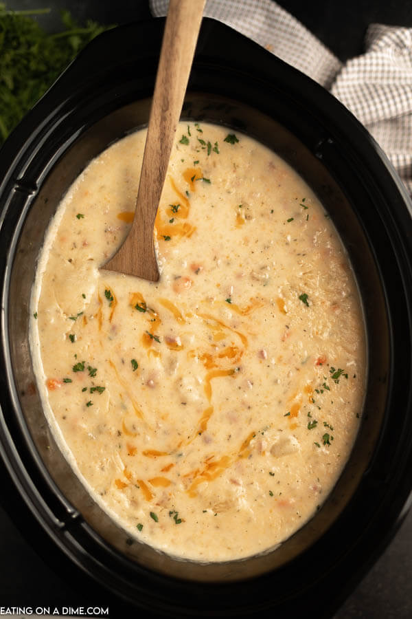 Crockpot of ham and potato soup topped with cheese. 
