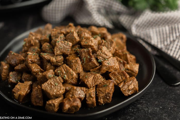 Dinner is a breeze when you make this easy Crock Pot Steak Bites Recipe. The entire family will love keto steak bites. Each bite is tender and delicious! Close up image of steak bites on a black plate.