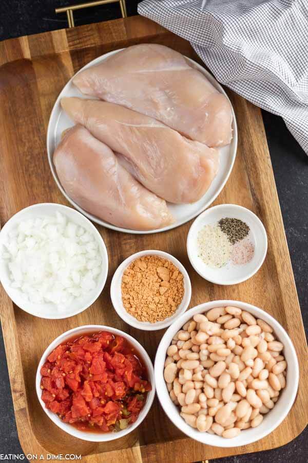 Close up image of ingredients for chicken taco soup - includes chicken breast, diced onion, seasoning, diced tomatoes and white beans. 
