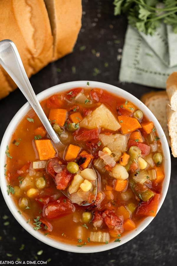 Close up image of vegetable soup in a white bowl with a spoon