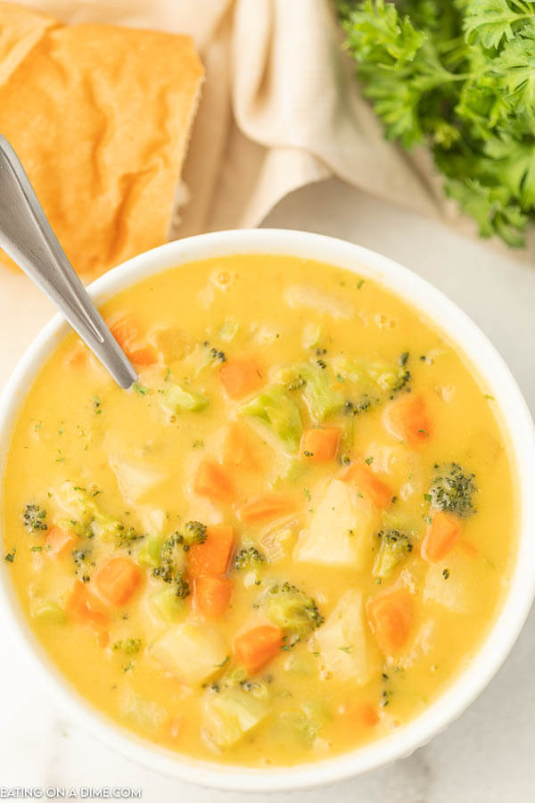 Close up image of creamy vegetable soup in a white bowl with a spoon. 