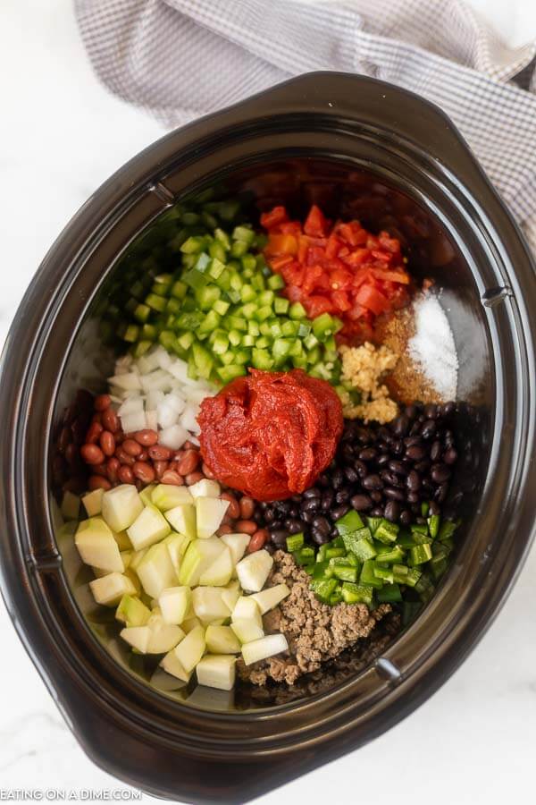Close up image of all ingredients for vegetable and beef chili in the crock pot uncooked. 