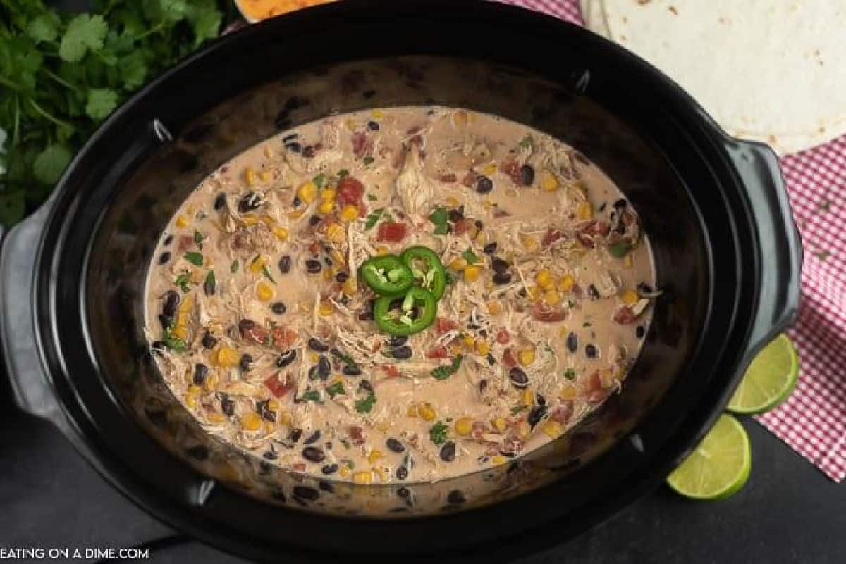 Crock Pot Fiesta Chicken Recipe is perfect for tacos, salads, burrito bowls and more! Crock pot Fiesta lime Chicken is creamy and tasty and sure to impress. Close up image of fiesta chicken in the crock pot.