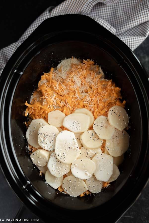 Close up image of scalloped potatoes in process of being layered in the crock pot. 