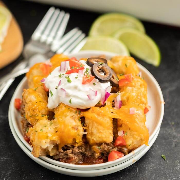 Close up image of beef enchilada tator tot casserole on a white plate. 