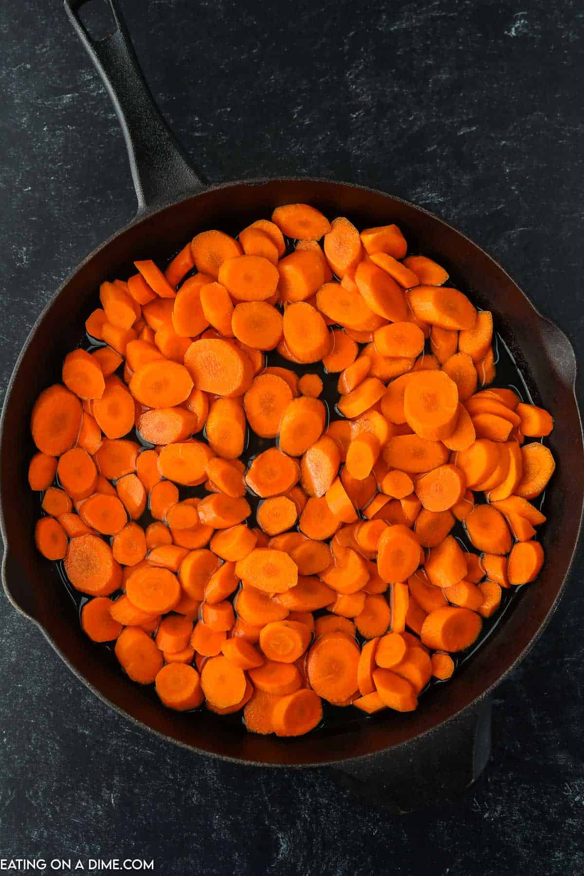 Placing slice carrots in a skillet with water