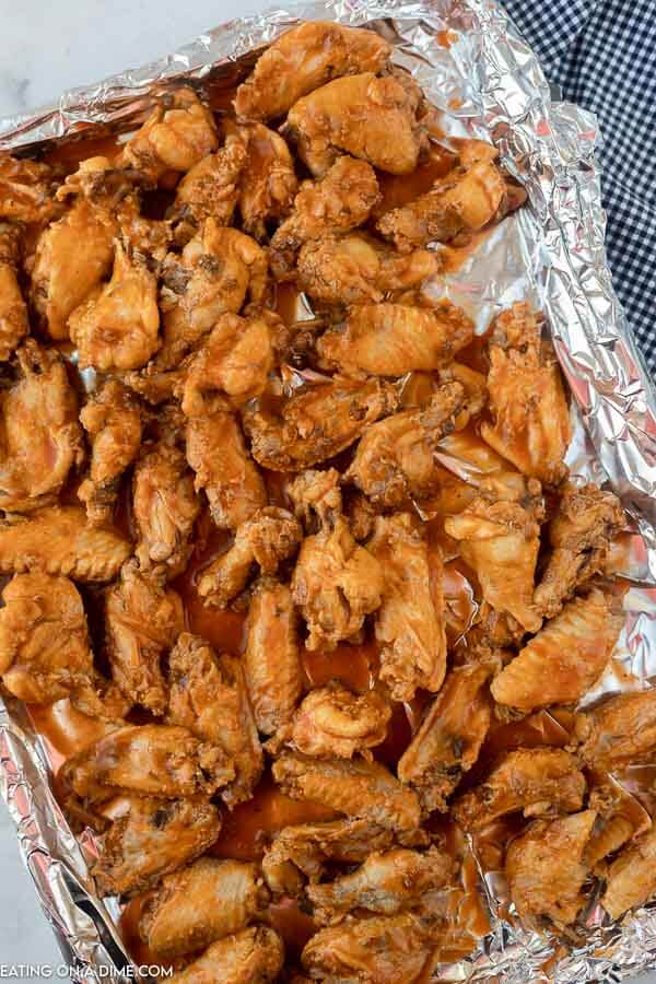 Close up image of chicken wings on a cookie sheet getting ready to go in the oven. 