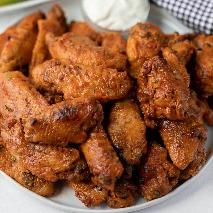 Close up image of chicken wings on a plate with a side of ranch. 