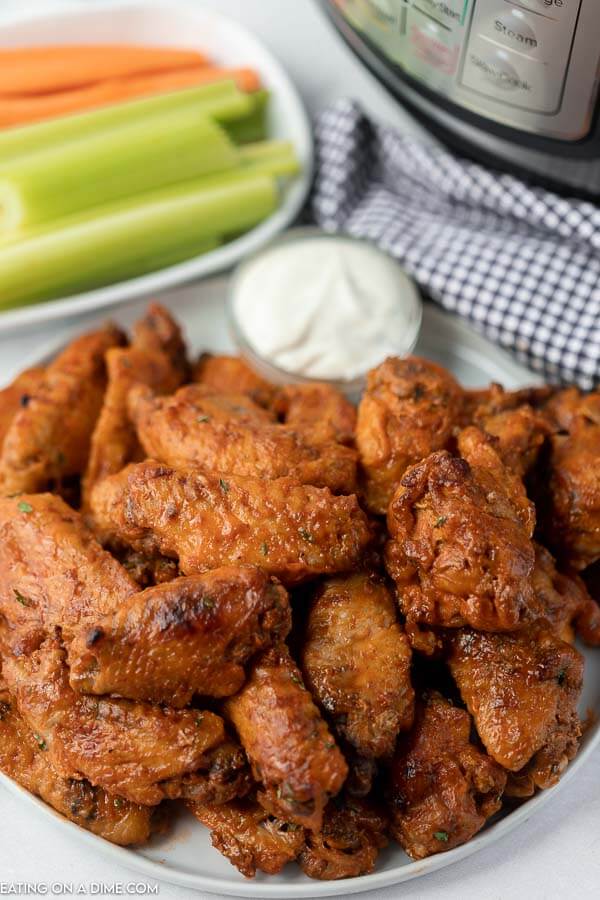 Close up image of chicken wings on a plate with a side of ranch and celery and carrots. 