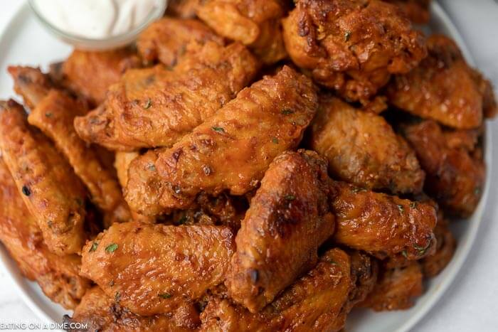 Close up image of chicken wings on a plate with a side of ranch. 