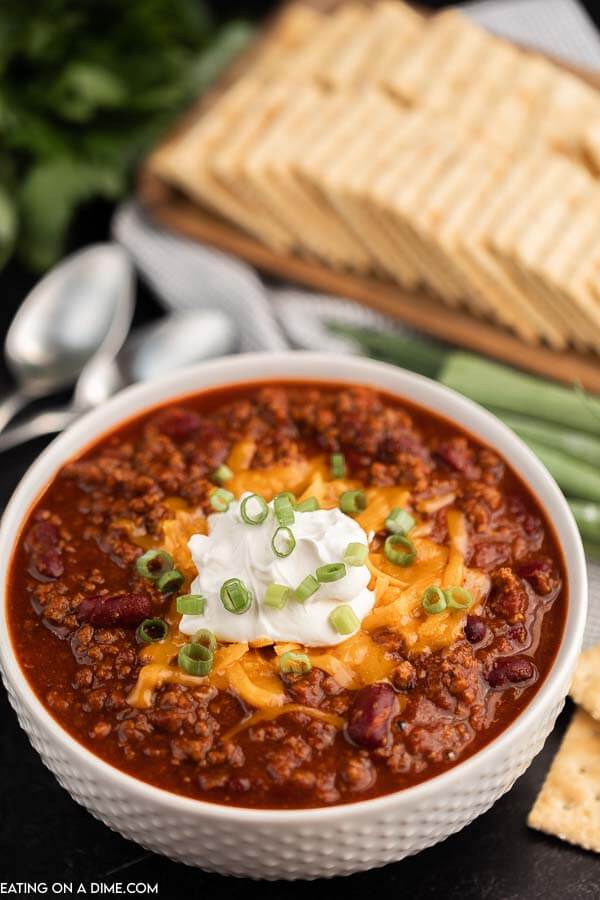 Bowl of chili topped with sour cream and cheese. 