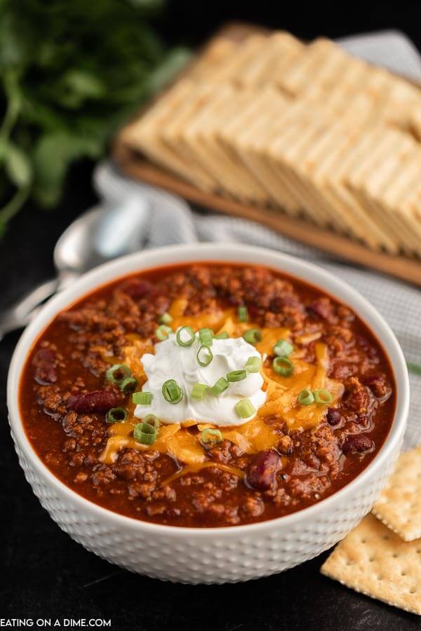 Bowl of chili topped with sour cream and cheese. 
