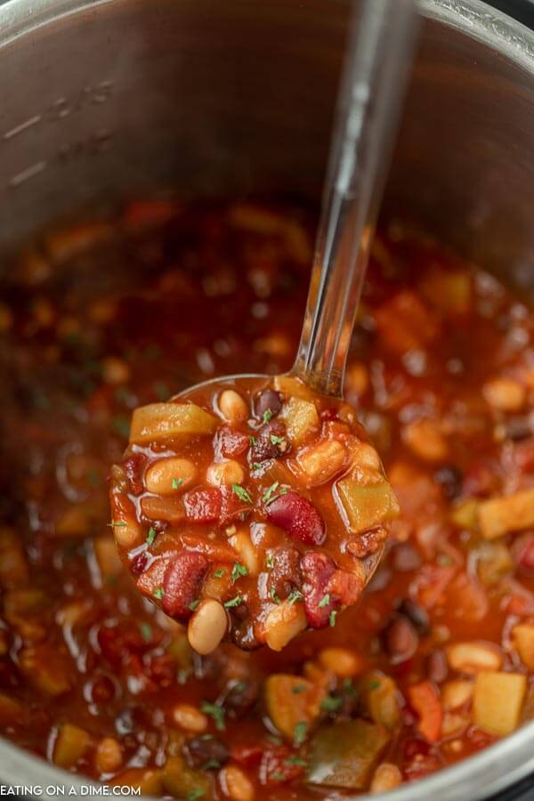 Close up image of vegetarian chili in the instant pot with a serving on a ladle. 