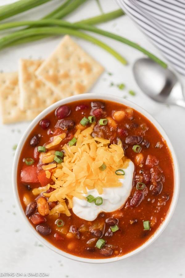 Close up image of vegetarian chili in a white bowl with a side of crackers. 