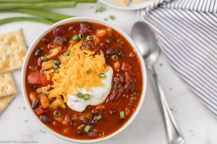 Close up image of vegetarian chili in a white bowl with a side of crackers and a spoon. 