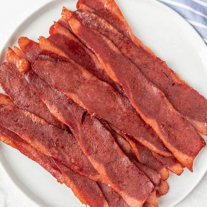 Close up image of cooked turkey bacon on a white plate. 