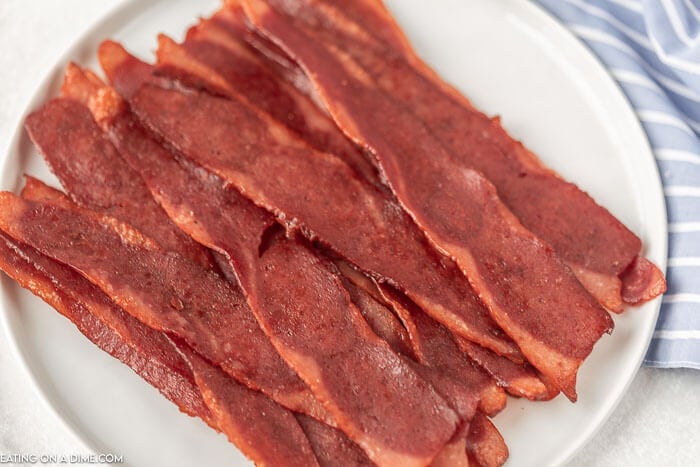 Close up image of cooked turkey bacon on a white plate. 