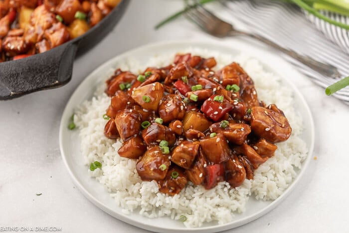 Skillet of pineapple chicken recipe on plate with rice. 