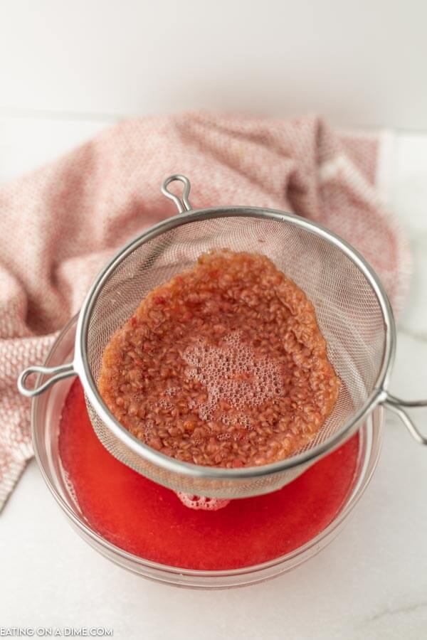 Close up image of  cooked raspberries in a strainer. 