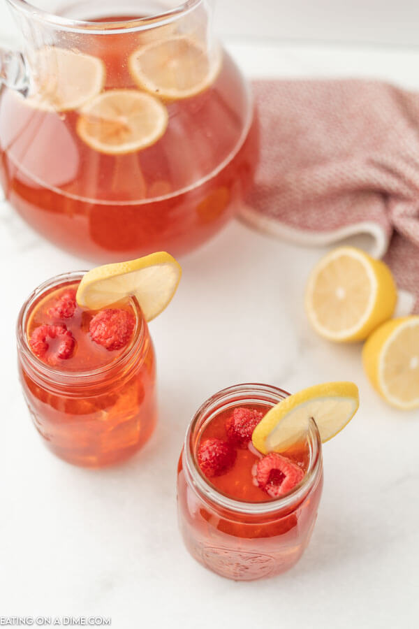 Close up image of mason jars with Raspberry Tea with slice lemons.