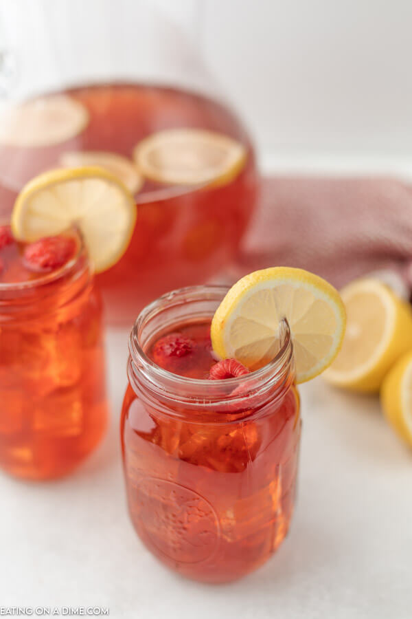 Close up image of Raspberry Ice Tea in a mason jar with a slice of lemon. 