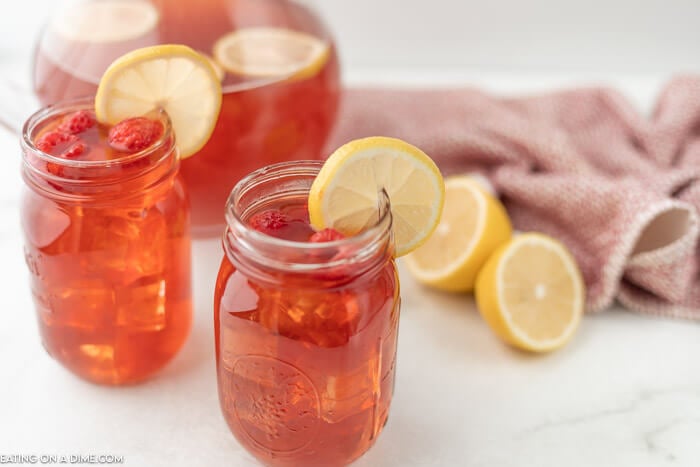 Close up image of mason jars filled with raspberry ice team with lemon. 