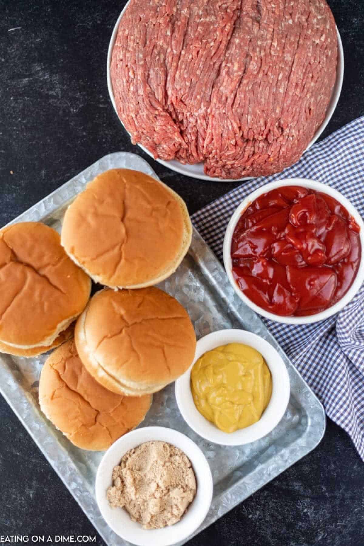 Close up image of ingredients for sloppy joes with hamburger buns on a platter. Yellow mustard, ketchup, brown sugar, ground beef