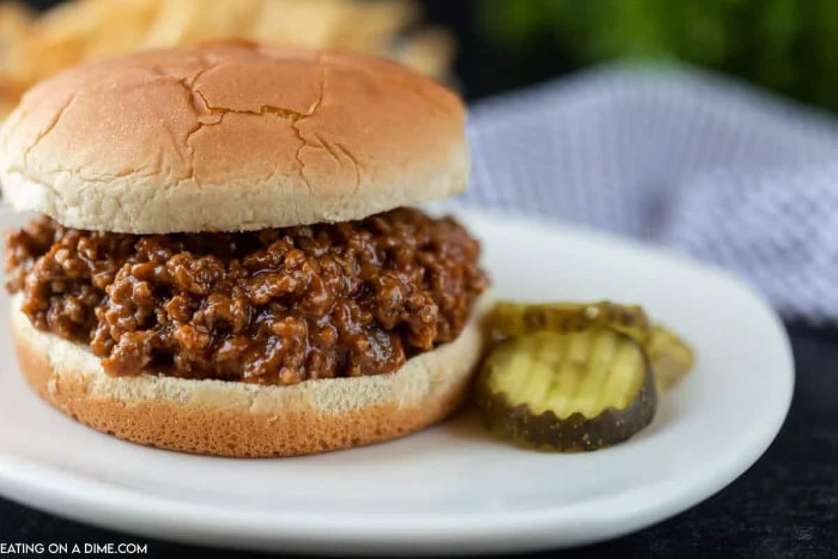 This easy Sloppy Joes recipe is easy to make and taste better than sloppy joes in a can. How to make sloppy joes with ketchup and just two more ingredients. Sloppy Joes Sandwich on a plate with slice pickles on the side