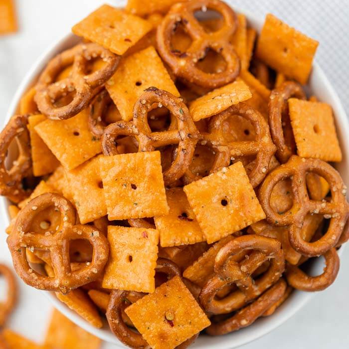 Close up image of cheez it snack mix in a white bowl. 