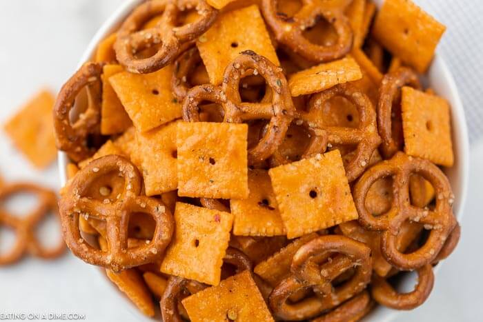 Close up image cheez it snack mix in a white bowl. 