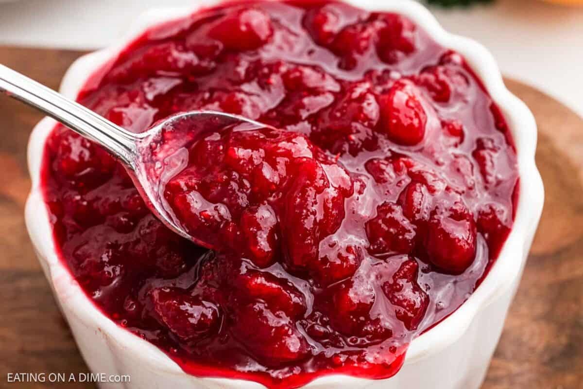 Cranberry sauce in a white bowl with a serving on a spoon.