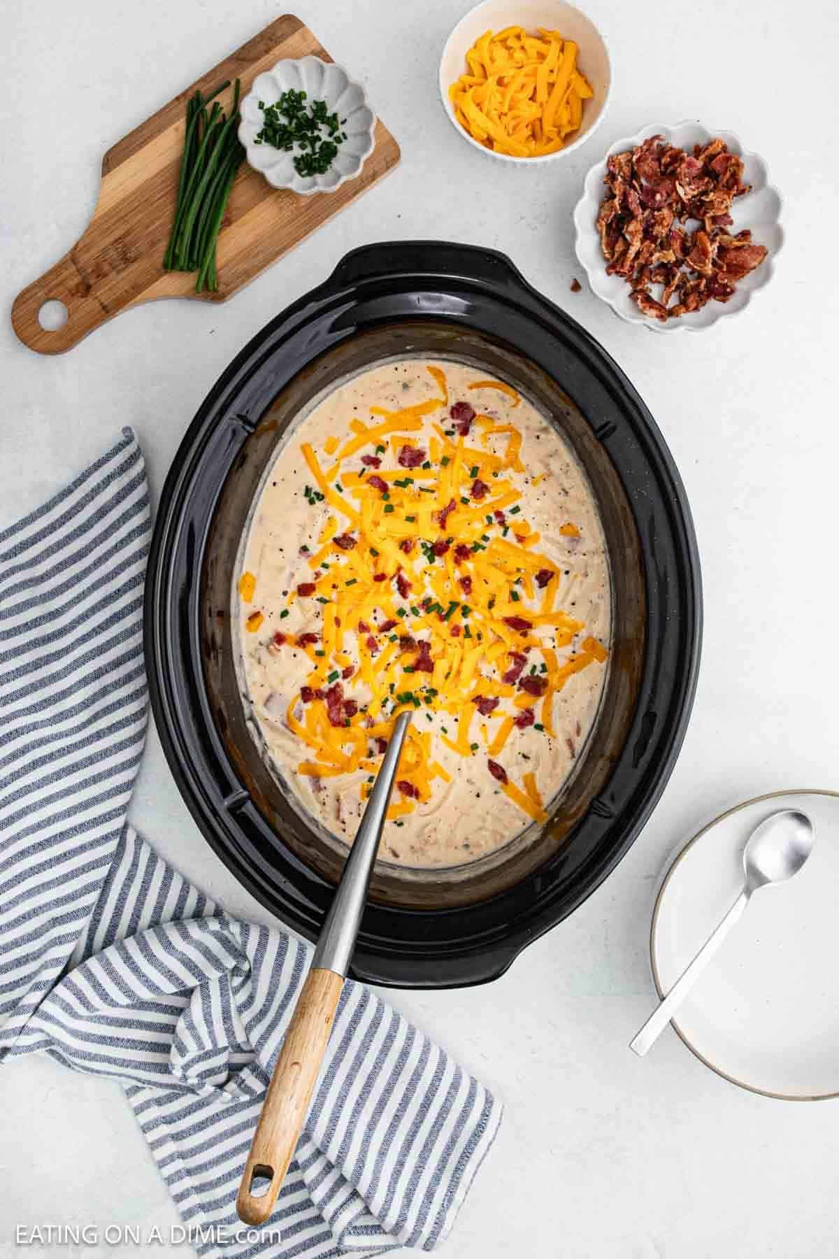 Cream soup in the crock pot topped with shredded cheese, bacon and green onions.