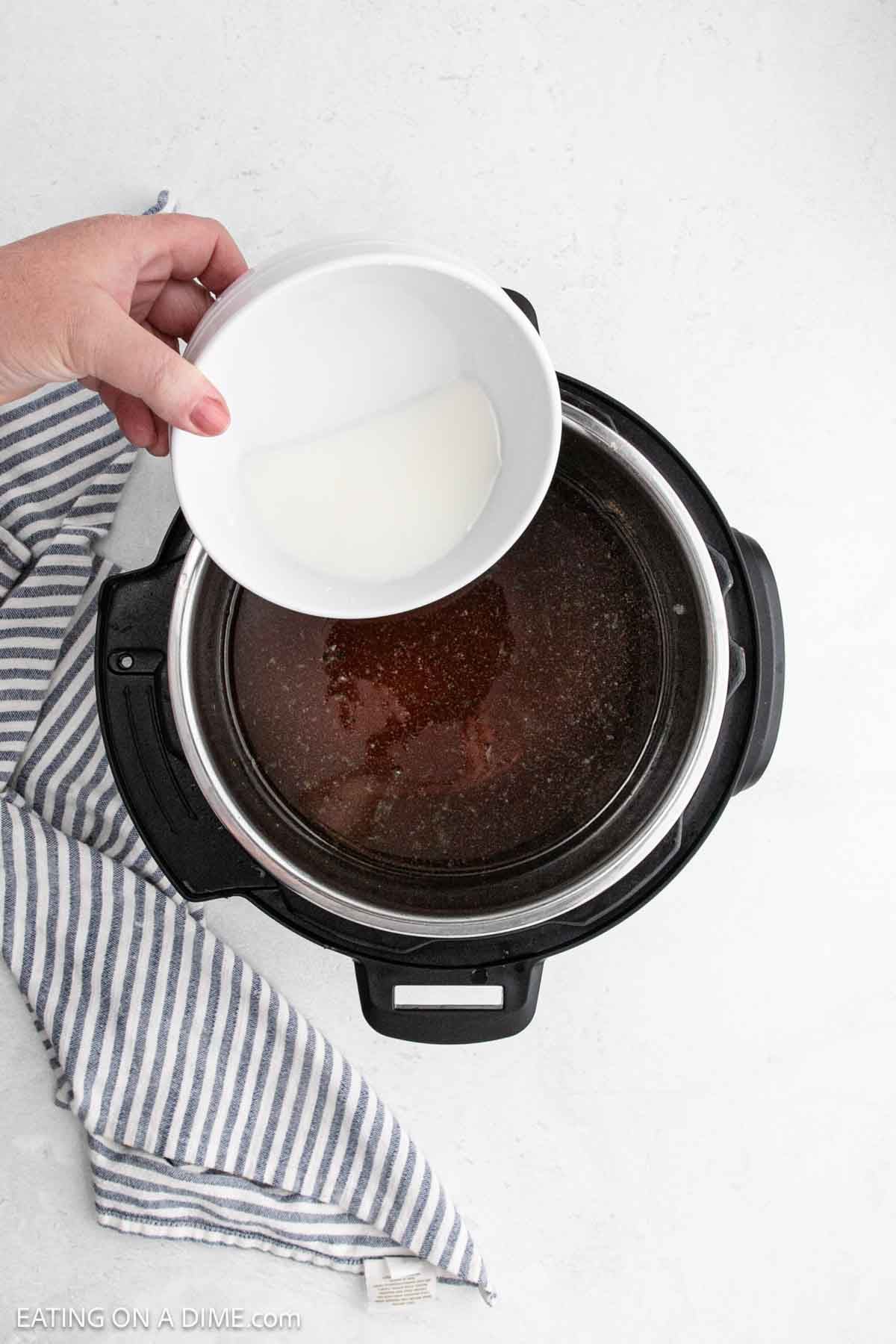 Pouring the cornstarch mixture in the instant pot with the gravy.