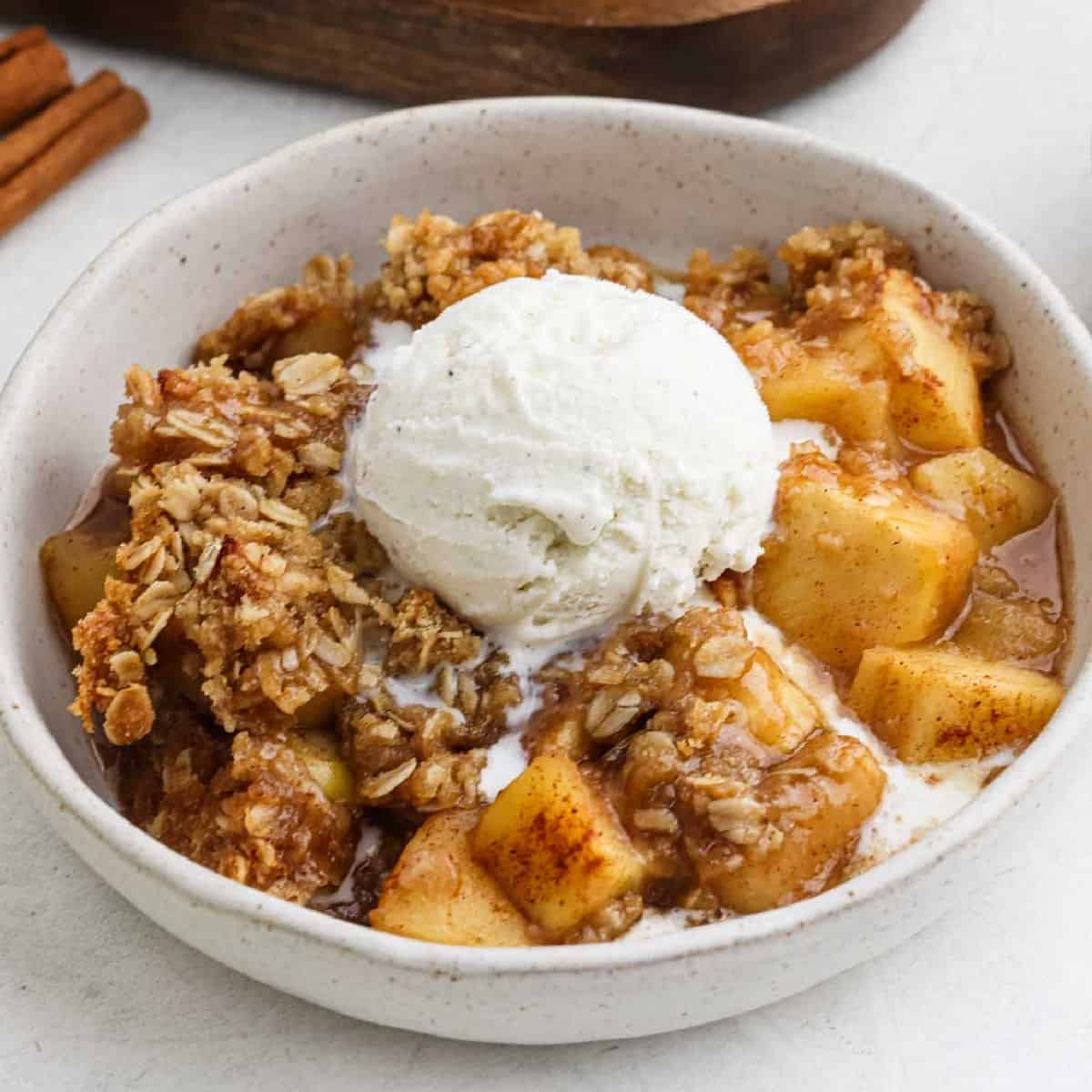 Apple crisp recipe topped with ice cream in a bowl.
