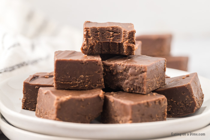 Close up image of chocolate peanut butter fudge stacked on a plate. 