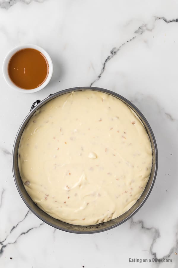 Pouring the cheesecake batter into the pan on top of the crust