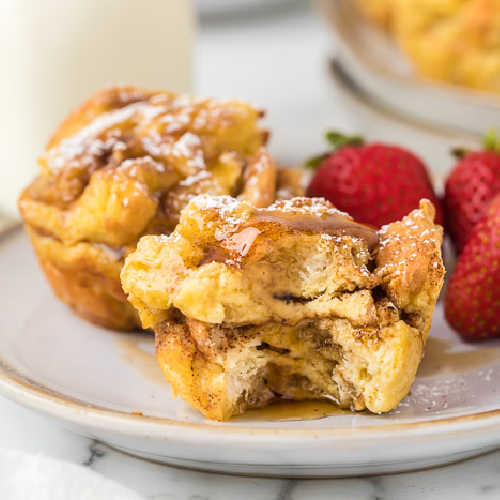 Close up image of French Toast Muffins on a white plate with a side of strawberries. 