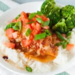 A white plate with rice and Monterey chicken on it.