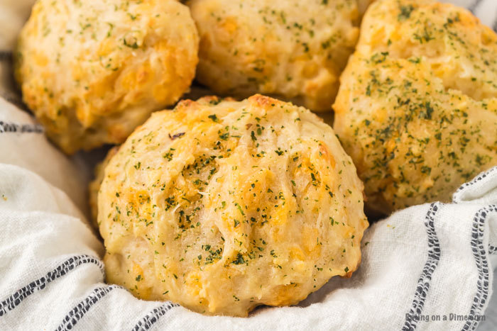 Close up image of cheddar bay biscuits in a bowl with a kitchen towel. 