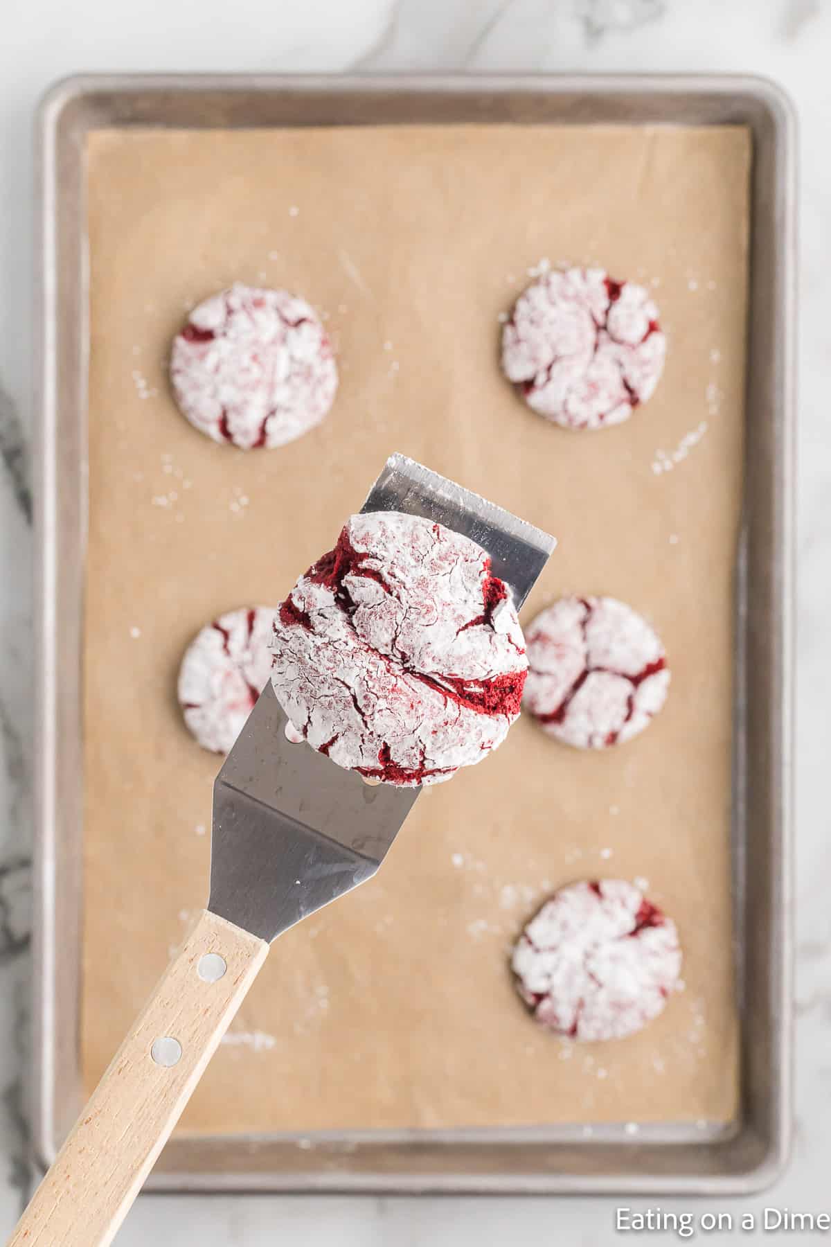 Red velvet cookies on a spatula and cookies on baking sheet