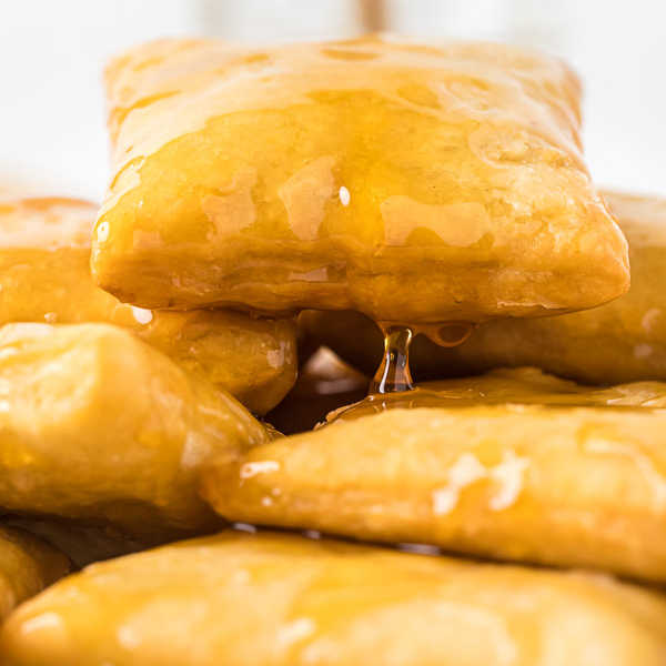 Close up image of sopapillas drizzled with honey. 