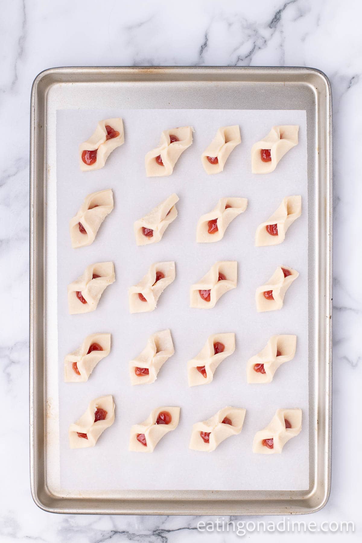 Uncooked strawberry pinch cookies on a baking sheet
