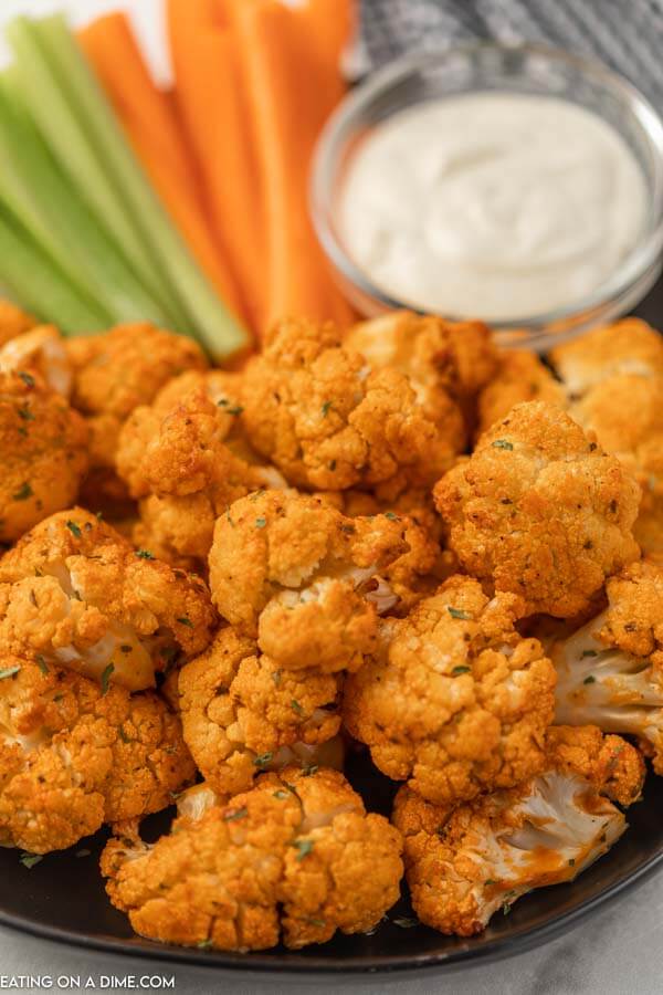 Plate of air fryer cauliflower with celery sticks and carrot sticks.  