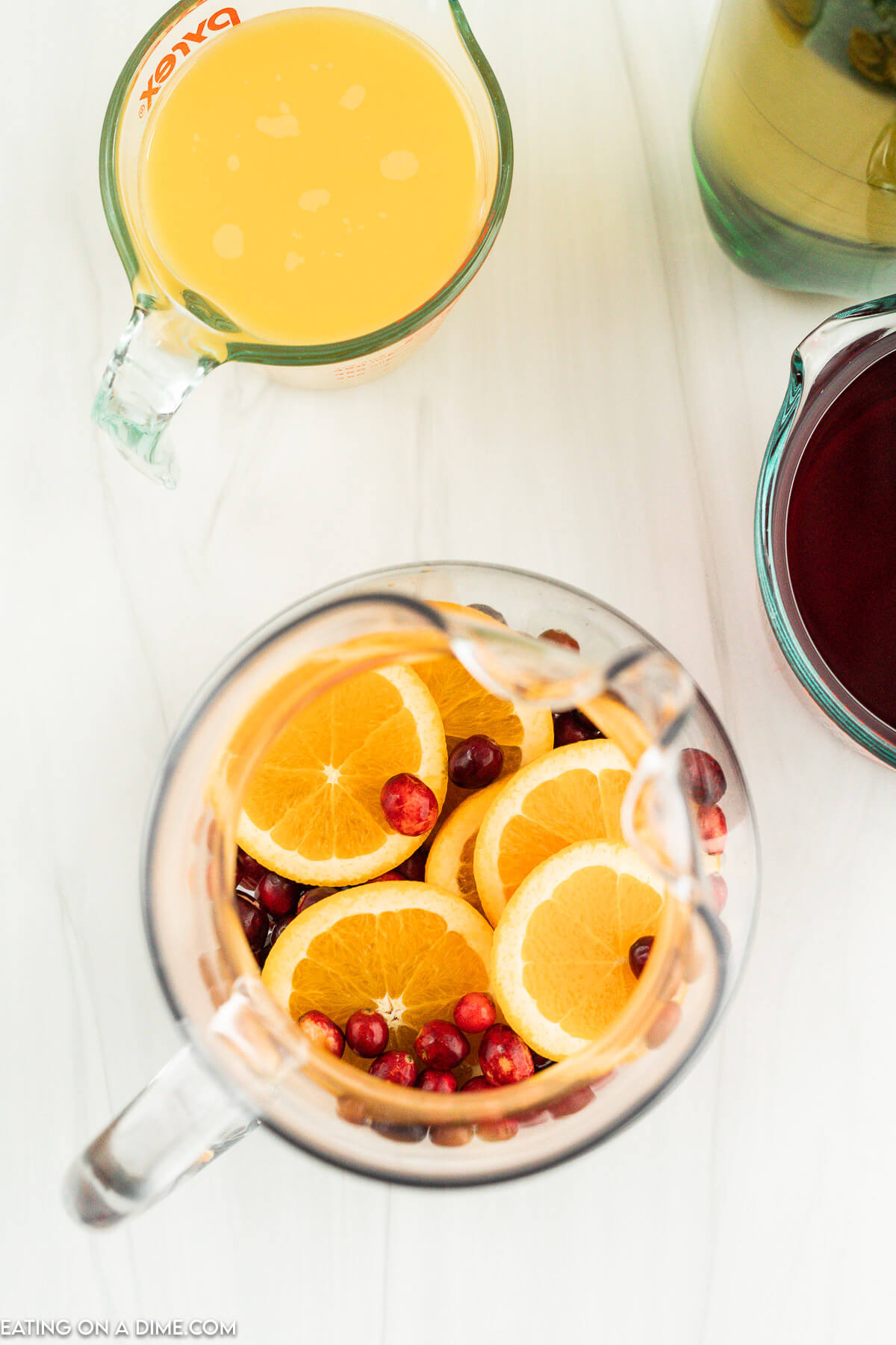 Placing the cranberries and orange slices in a large pitcher
