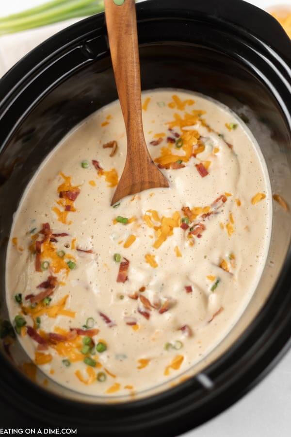 Crock Pot full of soup topped with cheese and bacon.