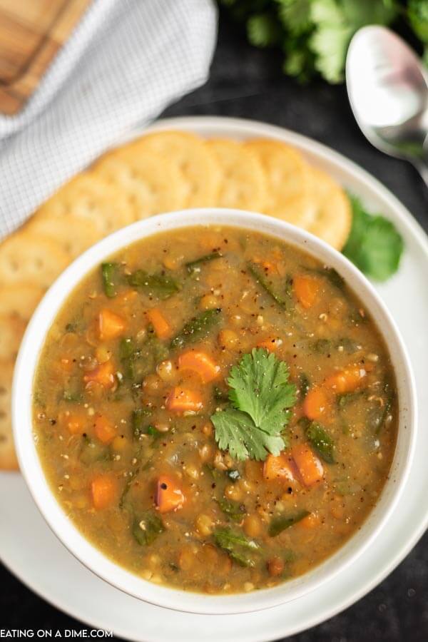 Bowl of lentil soup beside crackers. 