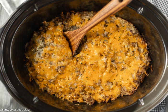 Close up image of Hamburger Casserole in the crock pot with a wooden spoon. 